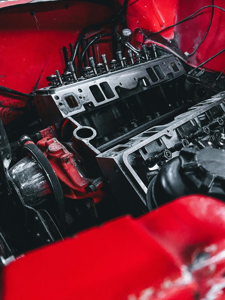 Detailed shot of a car engine within a vibrant red chassis, showcasing mechanical parts.